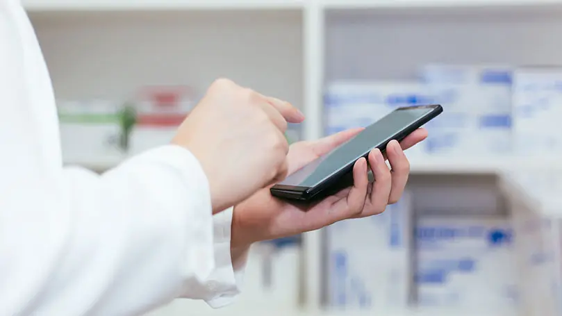 Nahaufahme Arme in weißem Kittel halten Smartphone