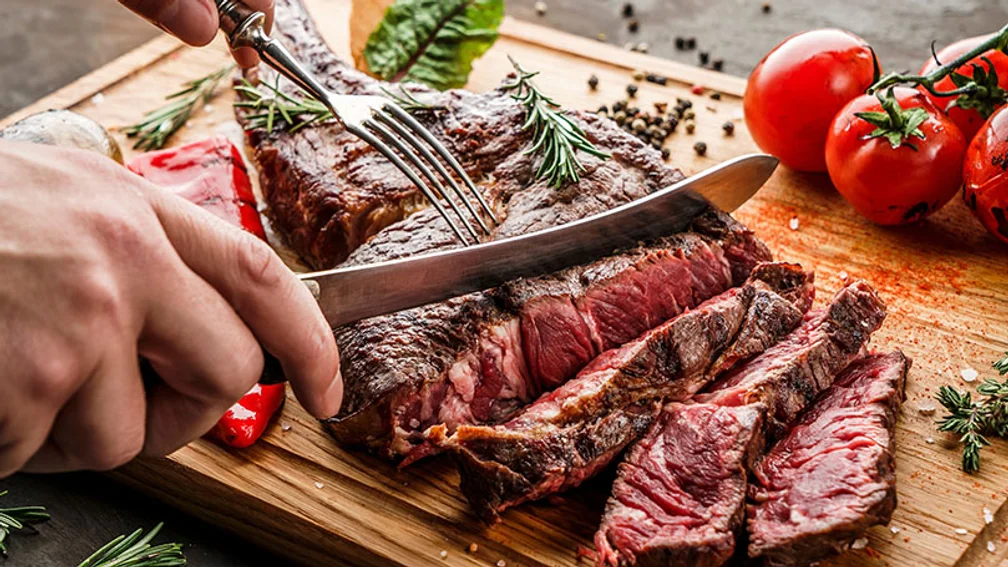 Mann schneidet ein Steak in Streifen