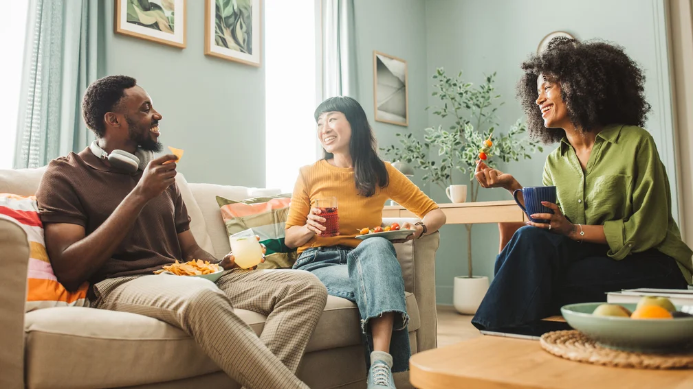 Gruppe von Freunde sitzt zuhause und essen Snacks