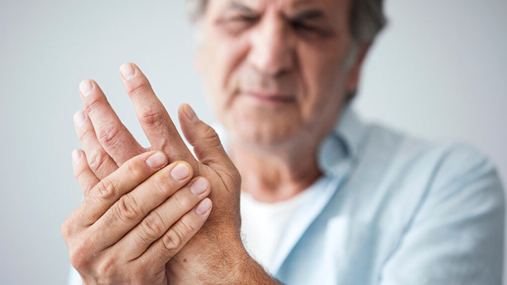 Mann hält sich schmerzende Hand
