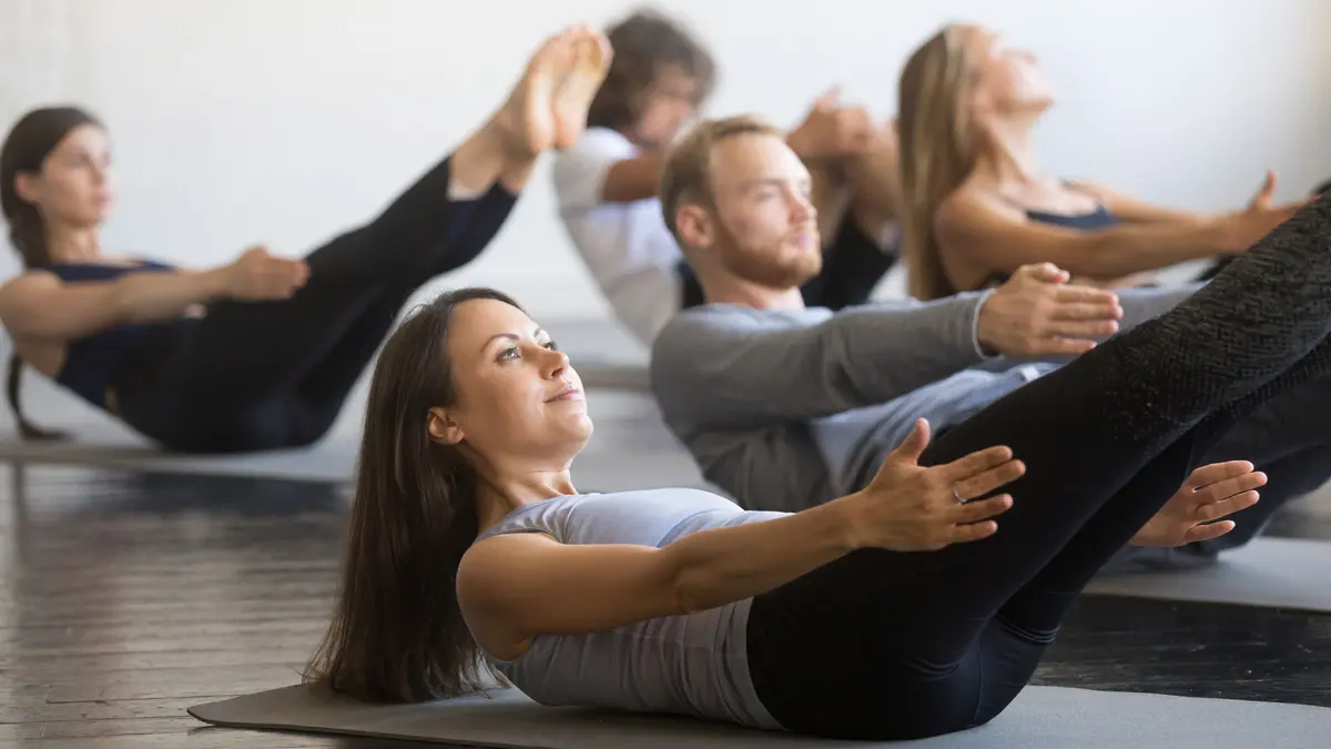 Gruppe junger Leute im Studio auf einer Fitnessmatte in Rückenposition