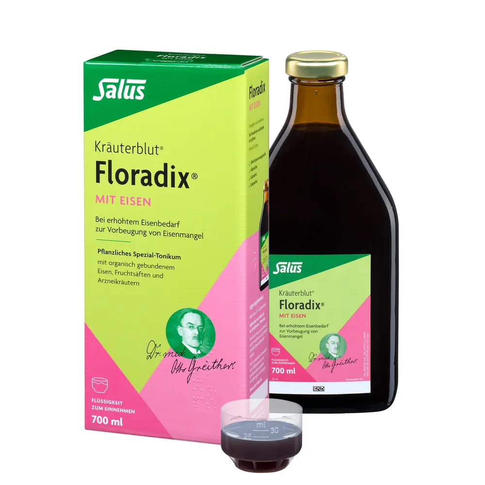 Links grün-rosa Floradix Verpackung, rechts die Braunglasflasche mit Floradix Aufschrift, im Vordergrund befüllter Messbecher mit Flüssigkeit