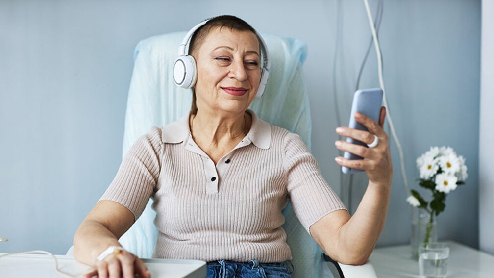 Frau mit kurzen Haaren im Krankenhaus schaut auf Smartphone