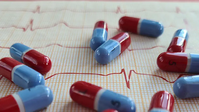 rot-blaue Kapseln liegen auf einem EKG-Diagramm
