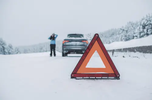 Warndreieck vorne, dahinter Person mit einer Autopanne