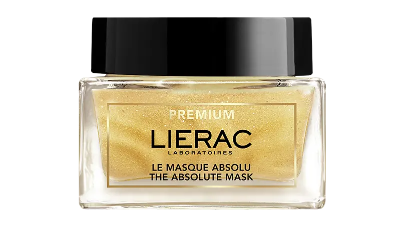 Frontale Ansicht einer goldfarbenen Gesichtsmaske in einem Glastopf mit schwarzem Deckel. Es trägt die Aufschrift Lierac.