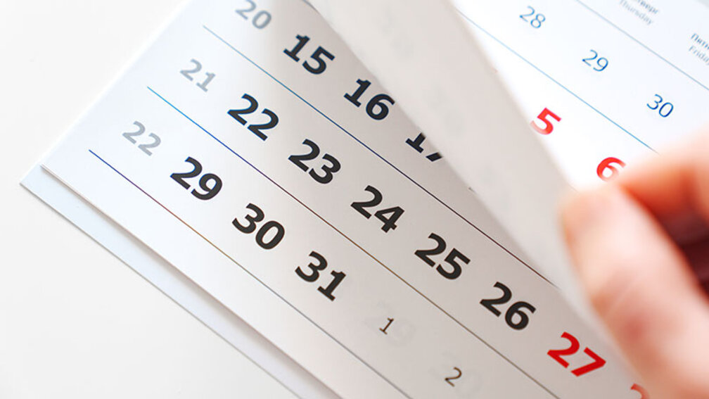 Männliche Hand blättert durch Kalender