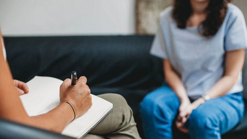 Frau sitzt auf der Couch bei einer Therapiesitzung