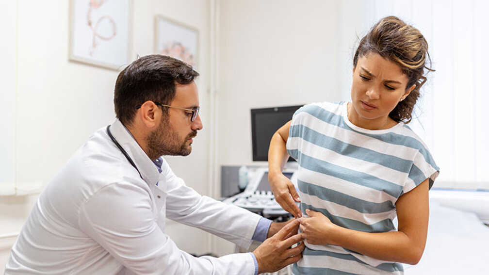 Arzt untersucht Patientin mit Schmerzen im Unterbauch