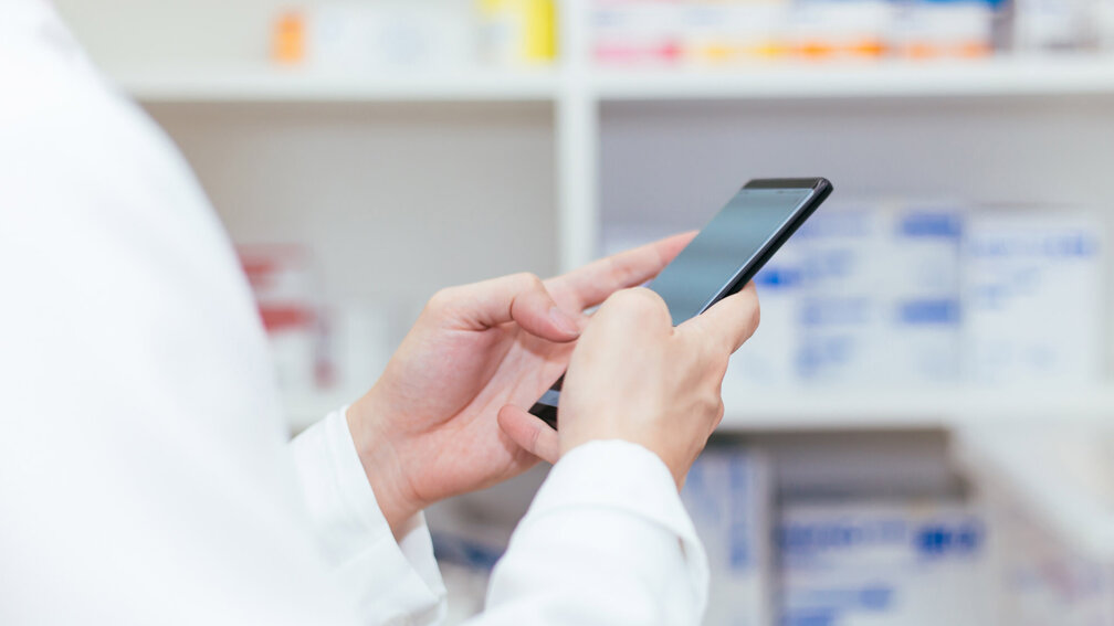 PTA in der Apotheke, hält Handy in den Händen
