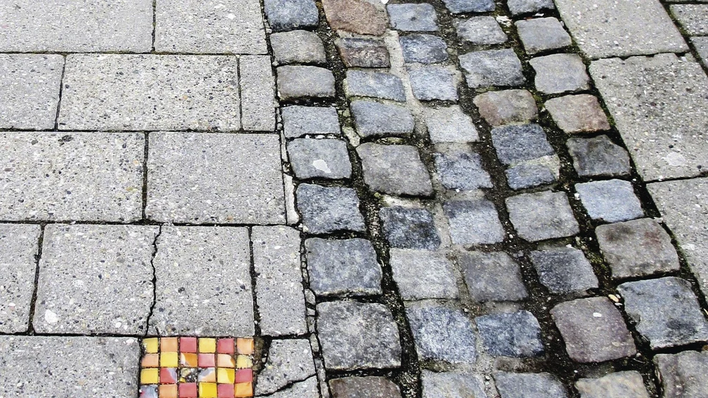 Buntes Mosaik anstelle eines herausgebrochenen Pflastersteins