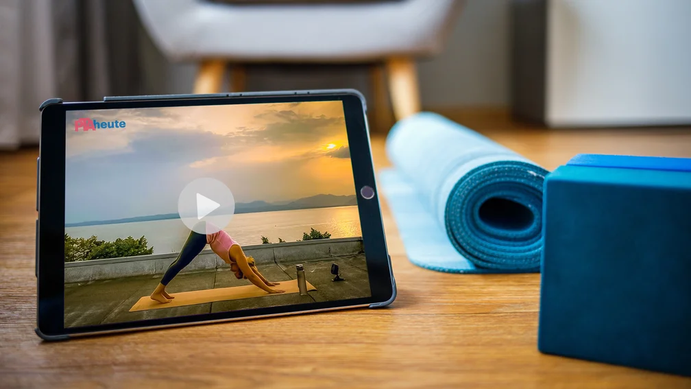 Frau sitzt vor Laptop und macht Yoga