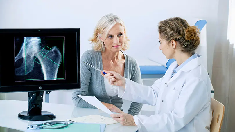 Ärztin erlöärt Patientin ein Röntgenbild, auf dem ein Hüftknochen abgebildet ist