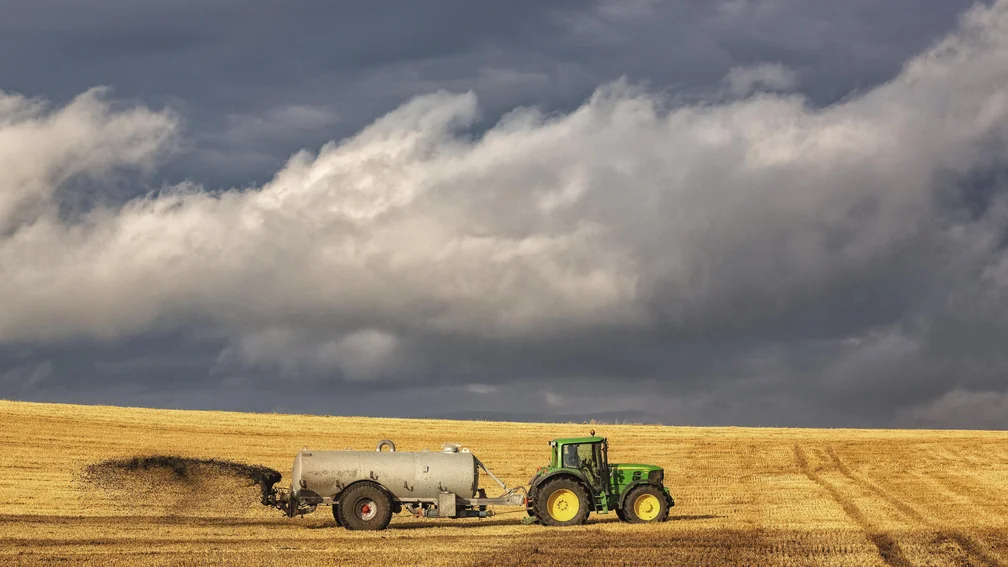 Ein Traktor fährt über das Feld und streut Gülle