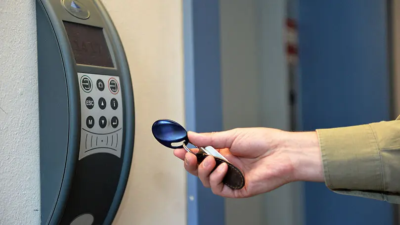 Arbeitszeiterfassungsanlage, davor wird mit der Hand ein Chip gehalten