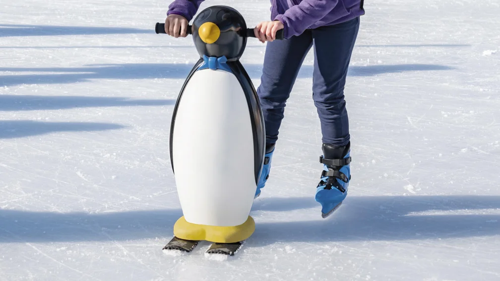 Kind auf Schlittschuhen mit Hilfspinguin