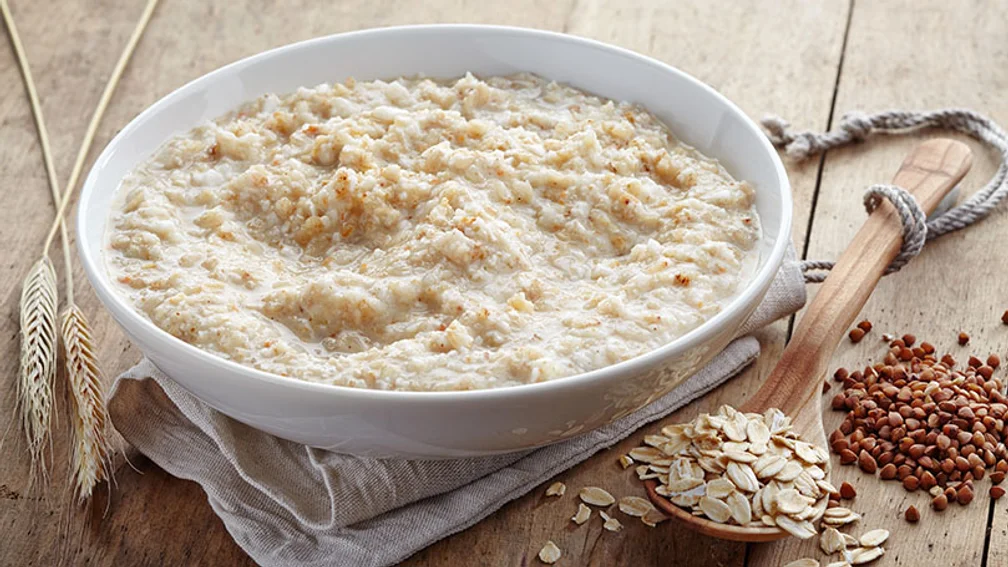 weiße Porzellanschale mit Haferbrei auf einem Baumwollehandtuch