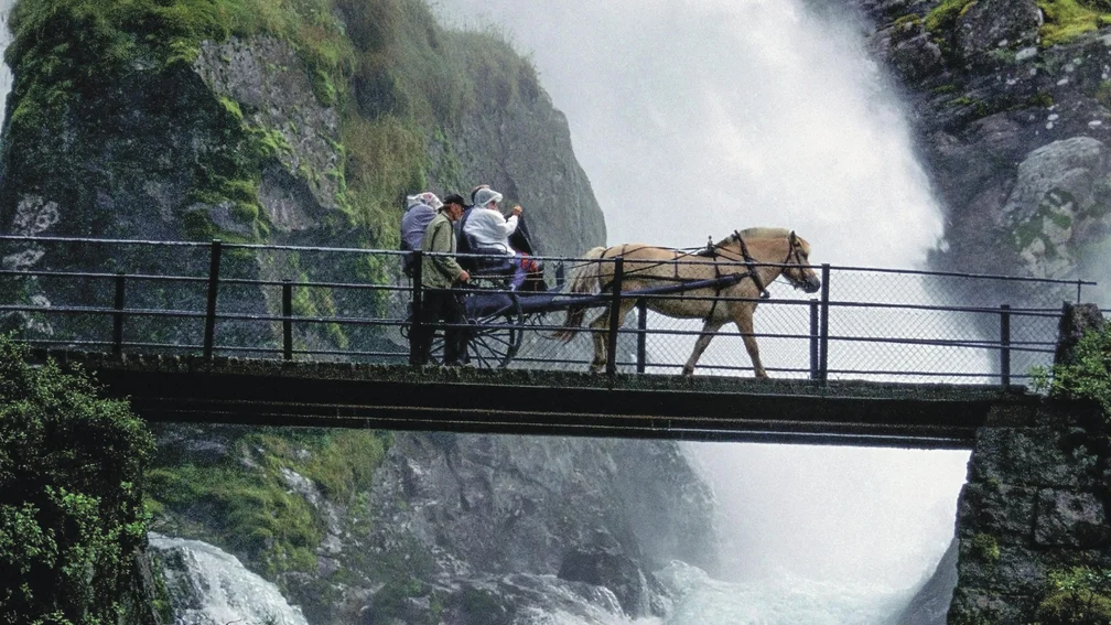 Pferdekutsche, welche über eine Brücke über einem Fluss fährt