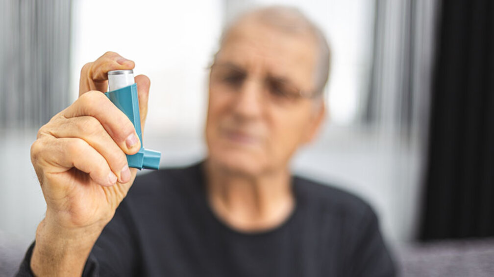 Älterer Mann hält Asthmaspray in der Hand