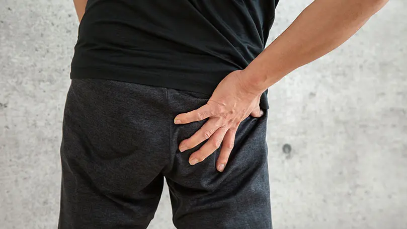 Mann legt Hand auf schmerzendes Gesäß
