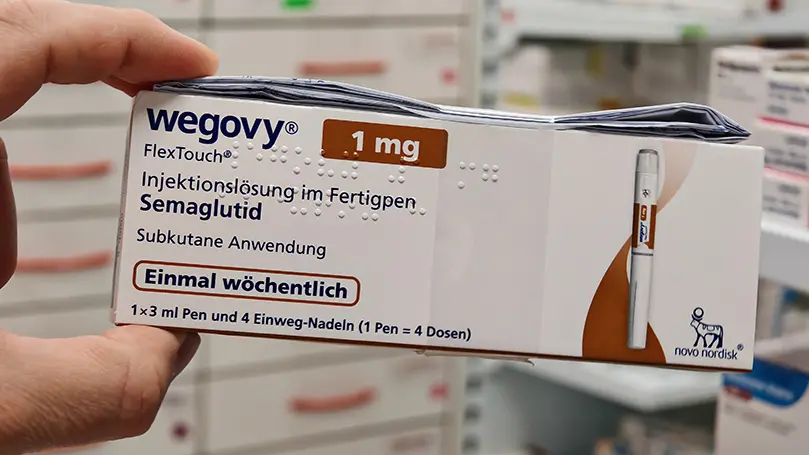 Hand hält Packung Wegovy 1 mg in die Kamera