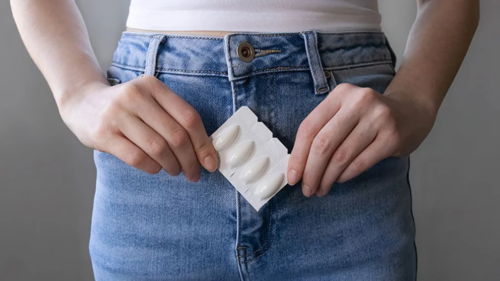 Frau hält Blsiter mit Vaginalzäpfchen vor ihren Schritt