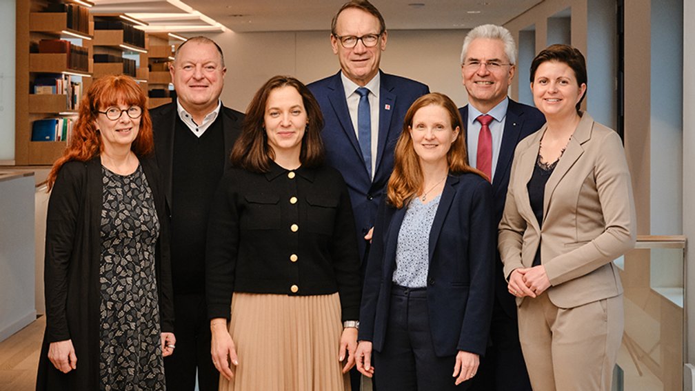 3 Männer und vier Frauen in gehobener Garderobe