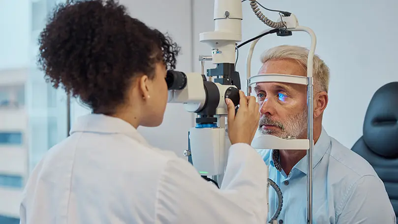 Augenärztin untersucht Auge eines Seniors