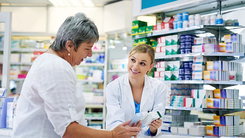 Apothekerin zeigt Patientin zwei Packungen