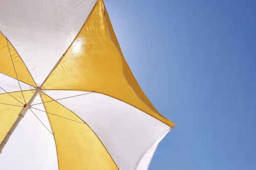 weiß-gelber Sonnenschirm vor blauem Himmel