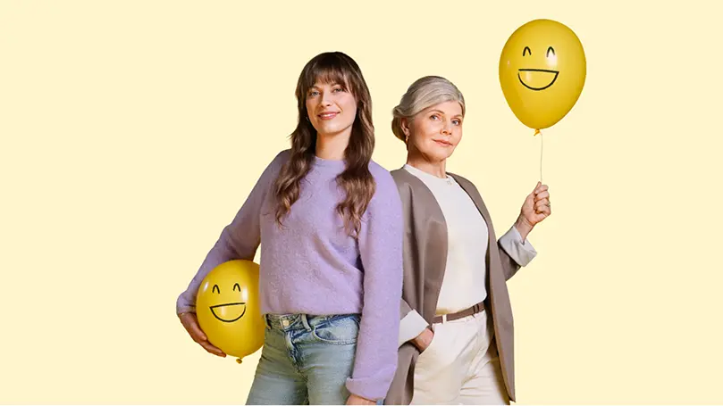 2 Frauen unterschiedlichen Alters haten je einen gelben Luftballon mit lachendem Smiley drauf in der Hand