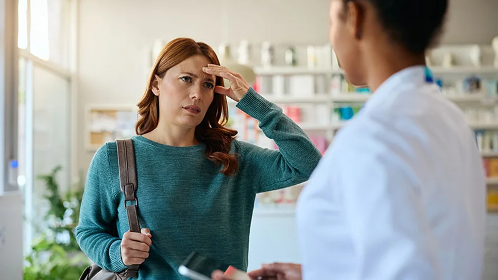 Frau mittleren Alters hält Hand an schmerzenden Kopf