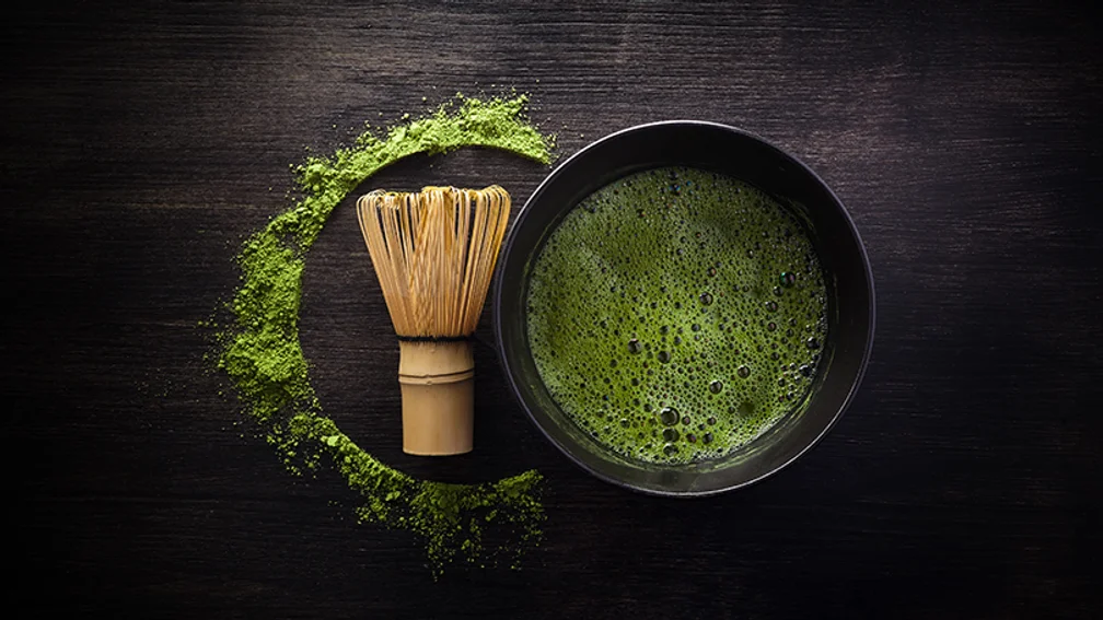 Matcha in schwarzer Schale neben Matcha-Pinsel