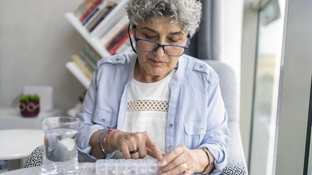 Frau holt Tabletten aus einer Tablettenbox