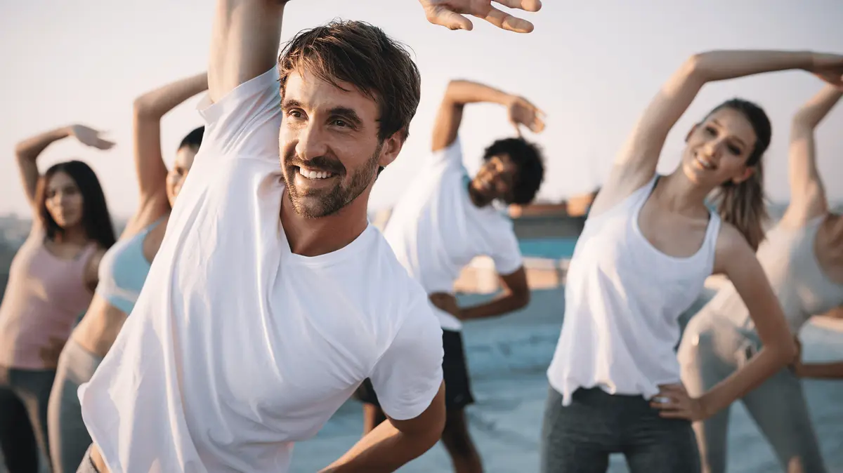 Eine Gruppe von Menschen bei gemeinsamen Dehnübungen während eines Outdoor-Fitnesstrainings.