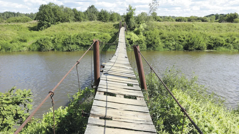 Holzbrücke mit vielen Lücken über einem Fluss