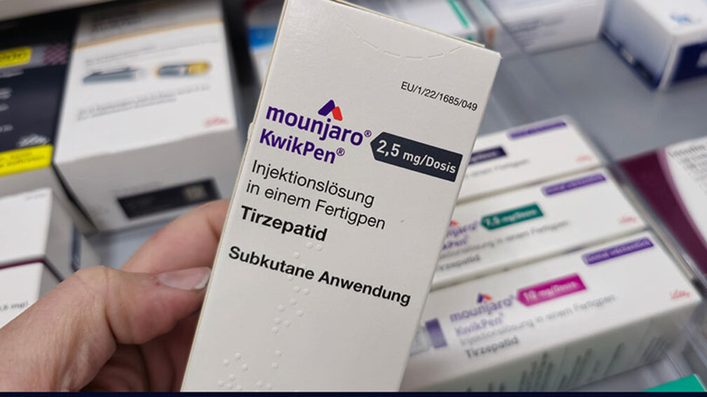 Hand hält Packung Mounjaro KwikPen in die Kamera