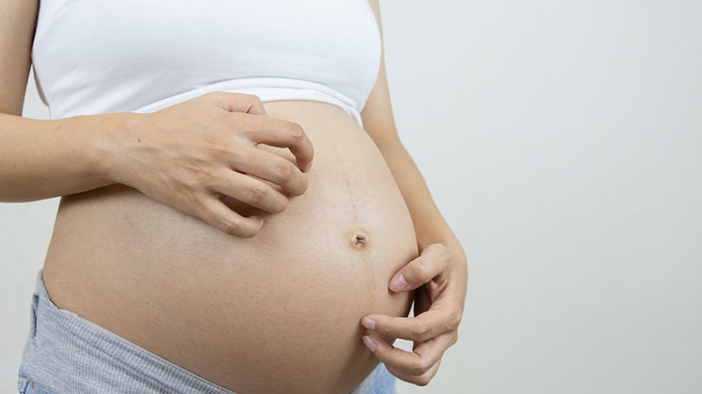 Schwangere kratzt sich ihren nackten Bauch