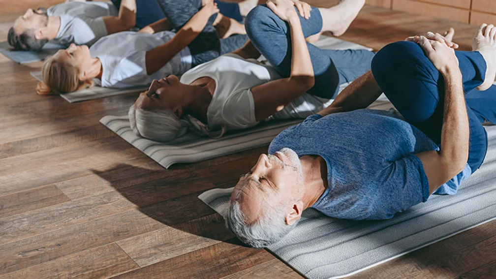 Vier Personen mittleren Alters dehnen sich beim Yoga