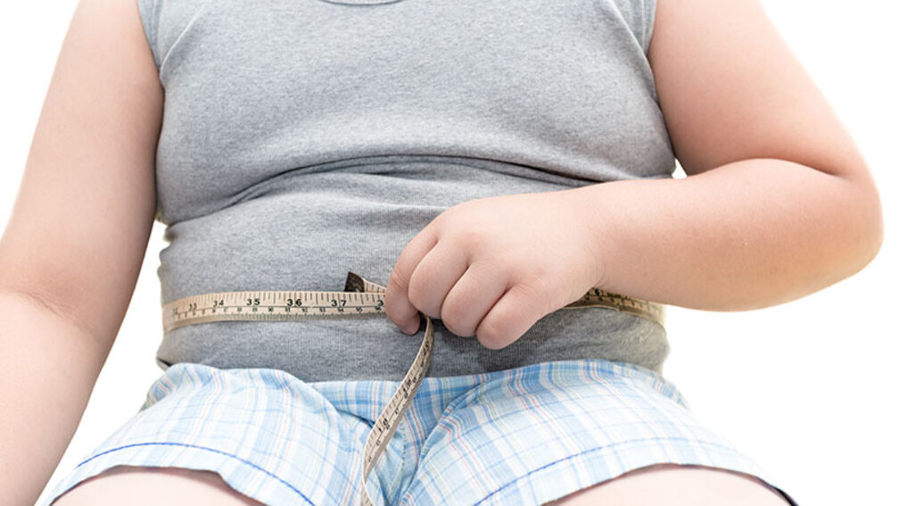 Dicker Junge hält Massband um Bauch