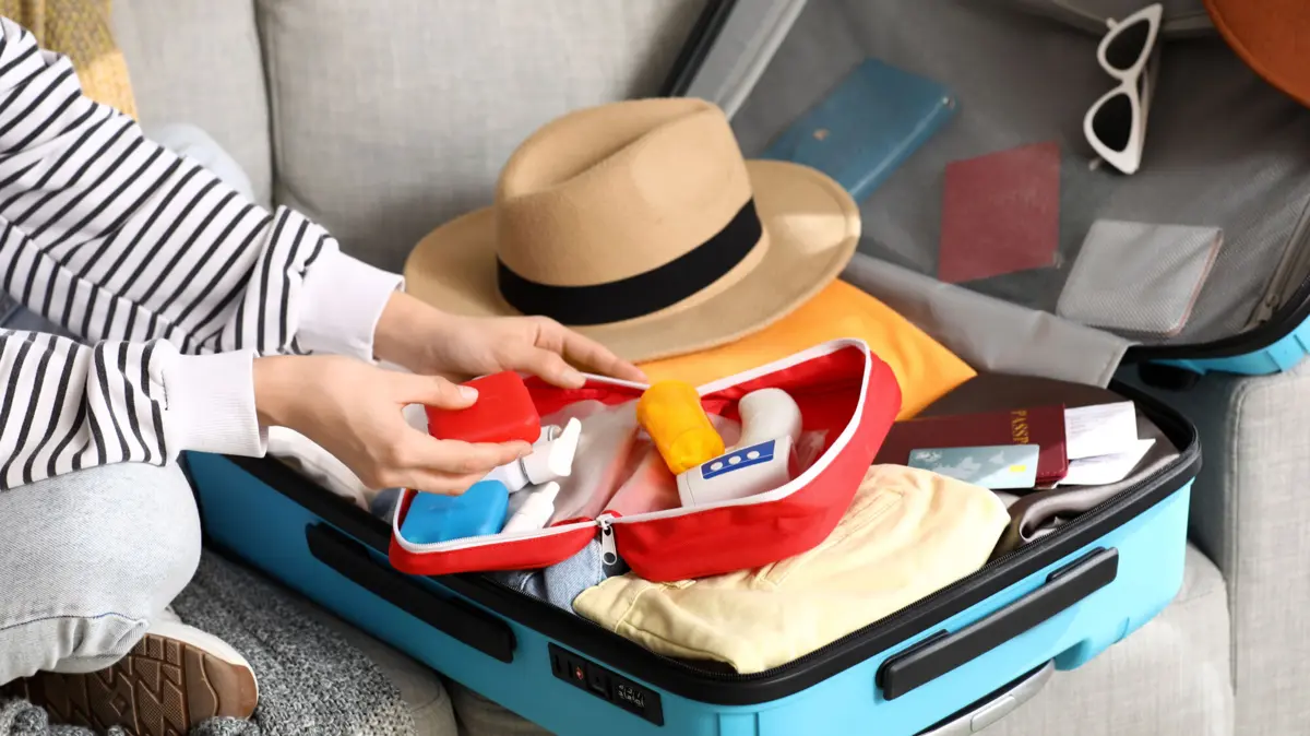offener Koffer mit Urlaubskleidung und Reiseapotheke