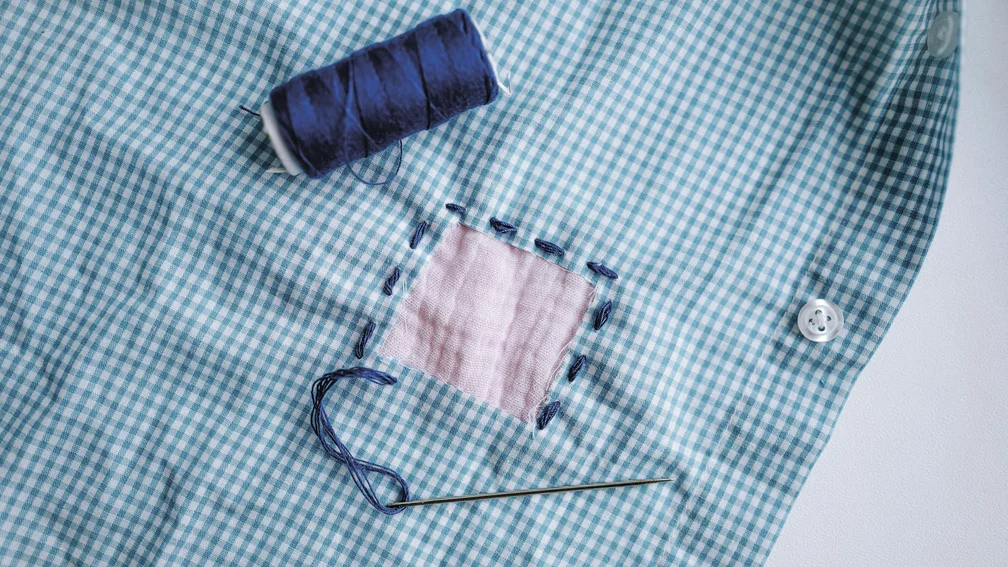 Karierte blaue Bluse mit einem rosa aufgenähtem Flicken