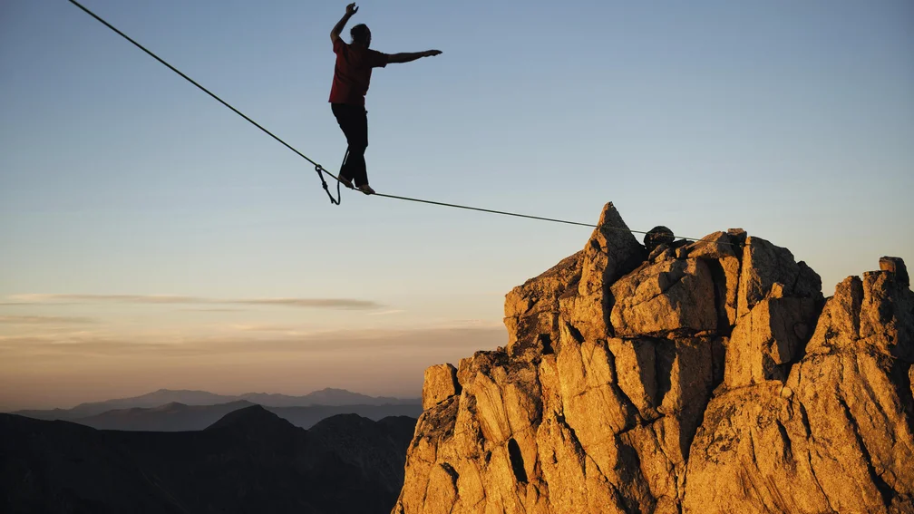 Silhouette eines Slackliners im Gebirge