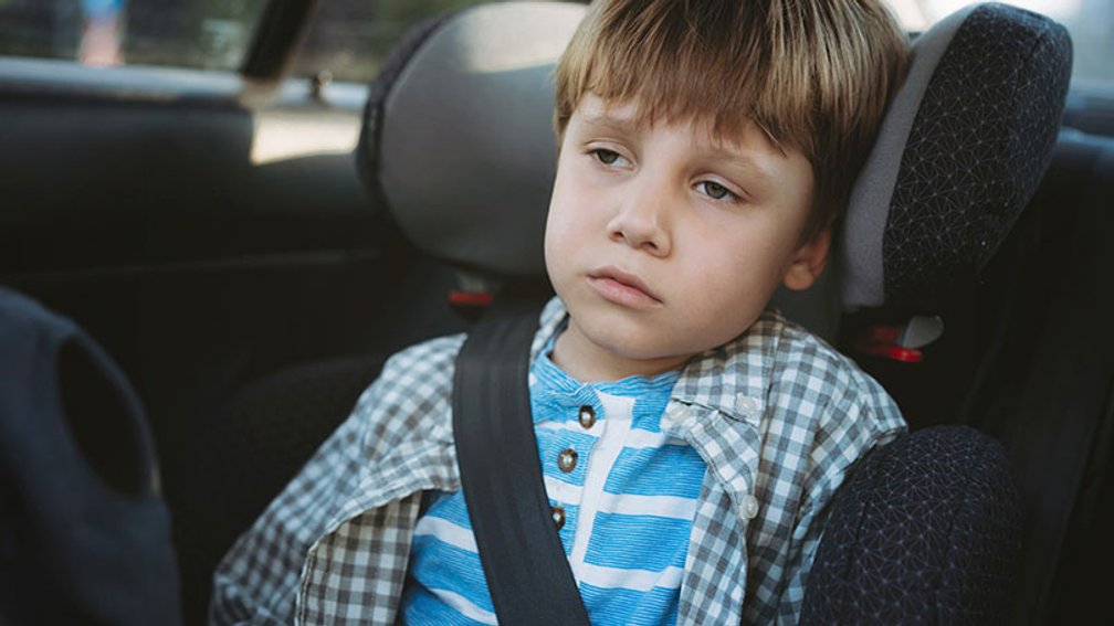 Junge im Kindersitz im Auto mit Übelkeit