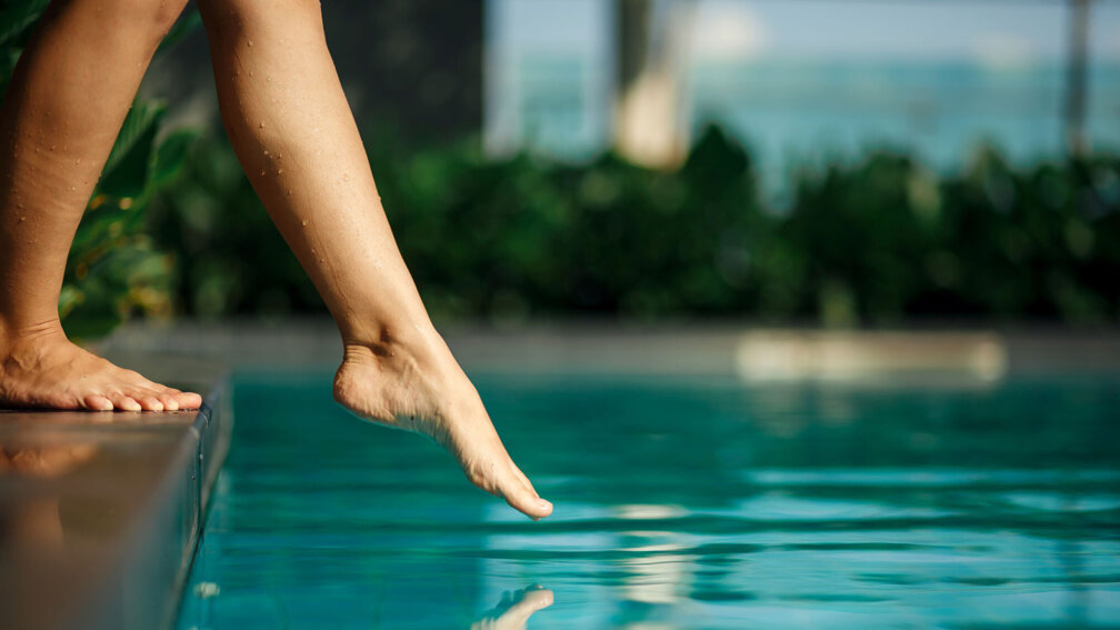 Frauenfüße laufen in Schwimmbecken rein zum Baden