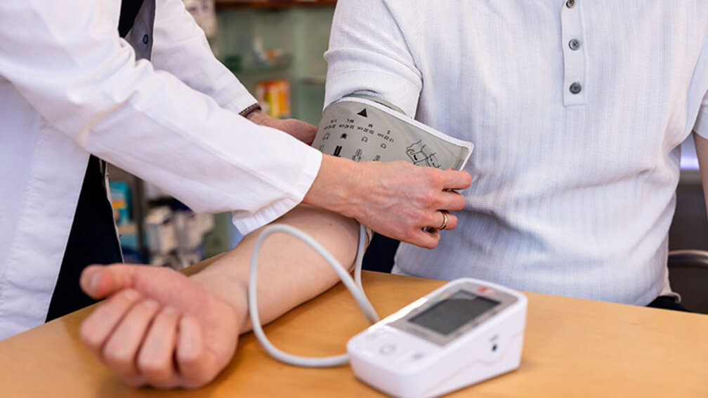 Apothekerin legt Kunden Blutdruckmanschette an