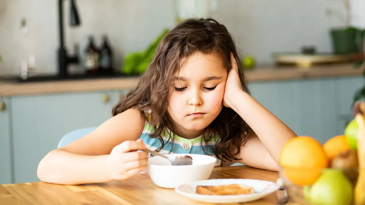 Mädchen sitzt am Tisch und will nicht essen