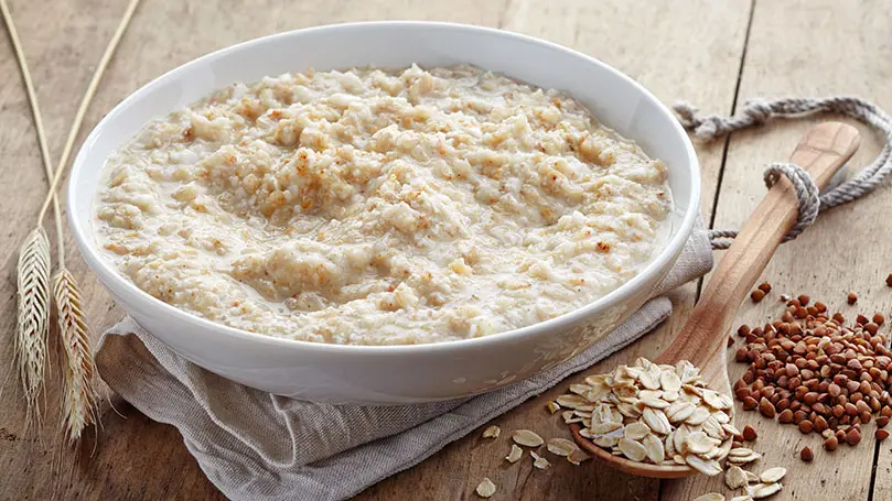 weiße Porzellanschale mit Haferbrei auf einem Baumwollehandtuch