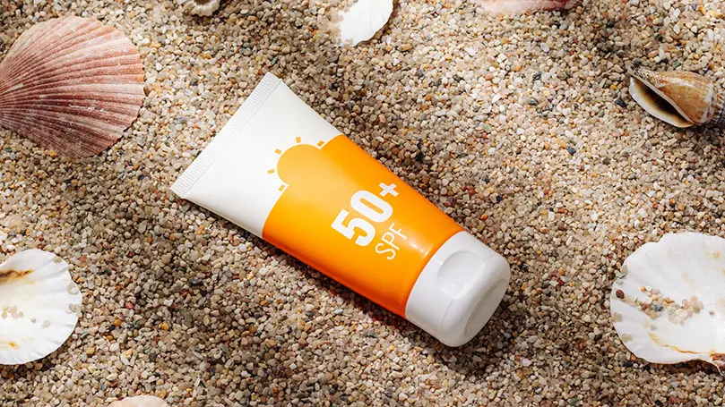 Tube Sonnencreme mit 50+ SPF auf feinem Kies