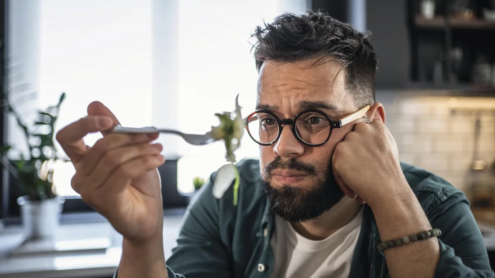 Mann schaut Gabel mit Essen an